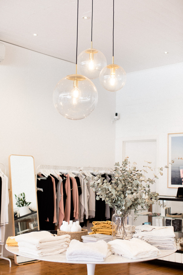 retail clothing shop interior with eucalyptus leaves in jar and round hanging glass lights