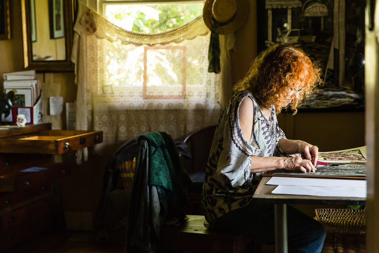 Artist Chris Lawry at work in her studio with dramatic window light