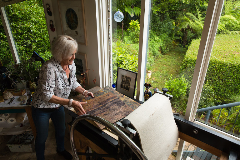 Artist Ches Mills working at her press making a print in her studio
