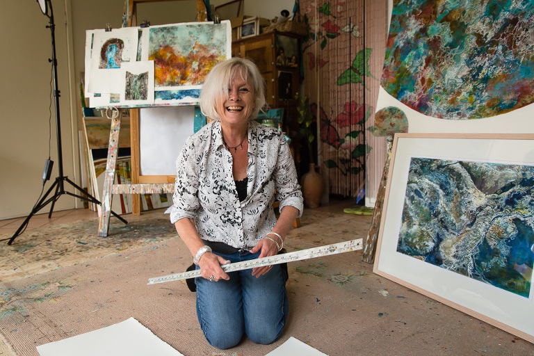 Artist Ches Mills sitting on the floor and laughing in her studio