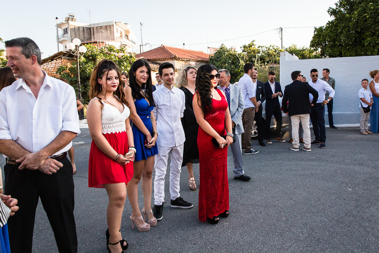 Brightly coloured well dressed wedding guests waiting outside for bride to arrive