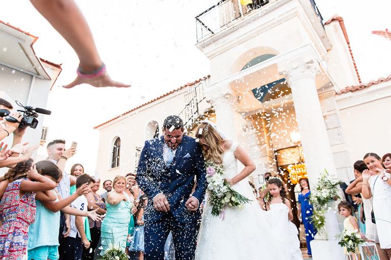 Bride and groom ducking and laughing as rice is thrown at them outside the church