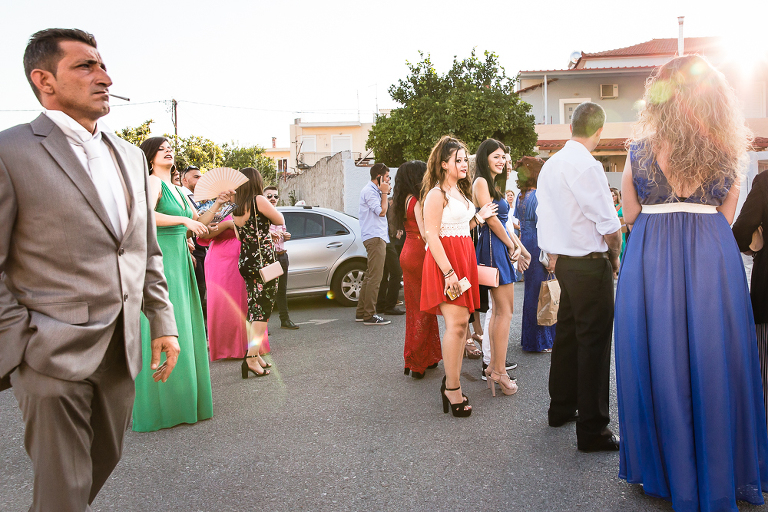 Brightly coloured well dressed wedding guests waiting outside for bride to arrive