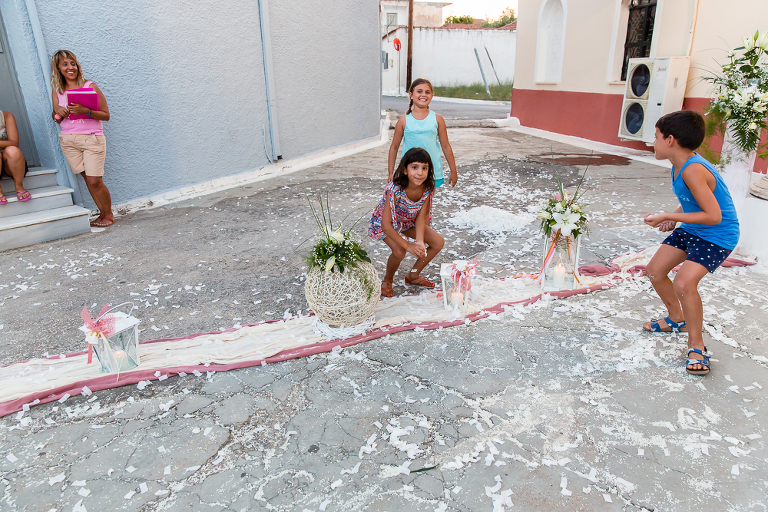 Children laughing playing with rice after Greek wedding in front of Greek church