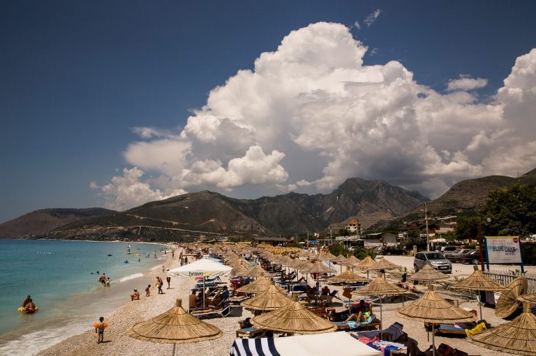 Organised beach resort at Borshe, Albanian Riveria, showing many straw umbrellas and bathers and large puffy clouds