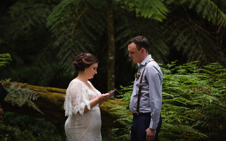 bride reading wedding vows to groom in outdoor ferny setting