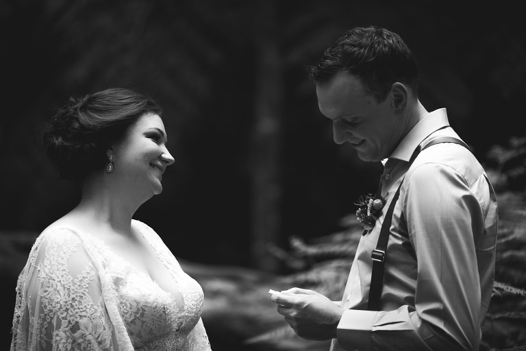 groom reading wedding vows to smiling bride in outdoor ferny setting