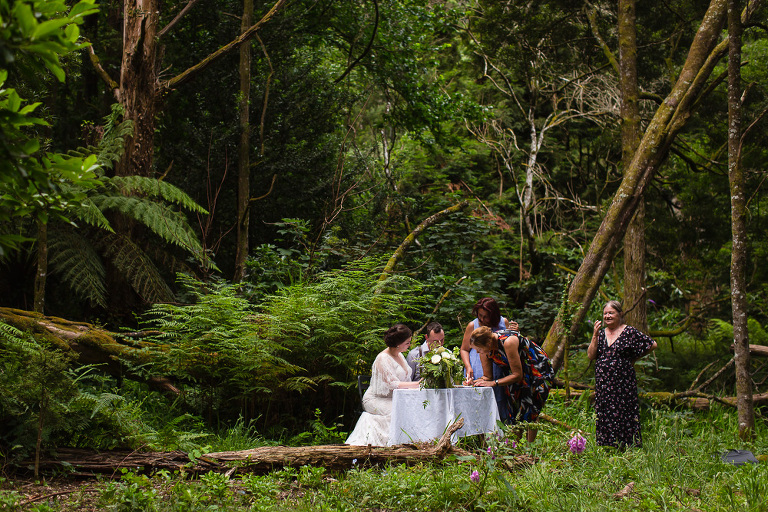 wedding party signing certificate at table in outdoor bush forest setting