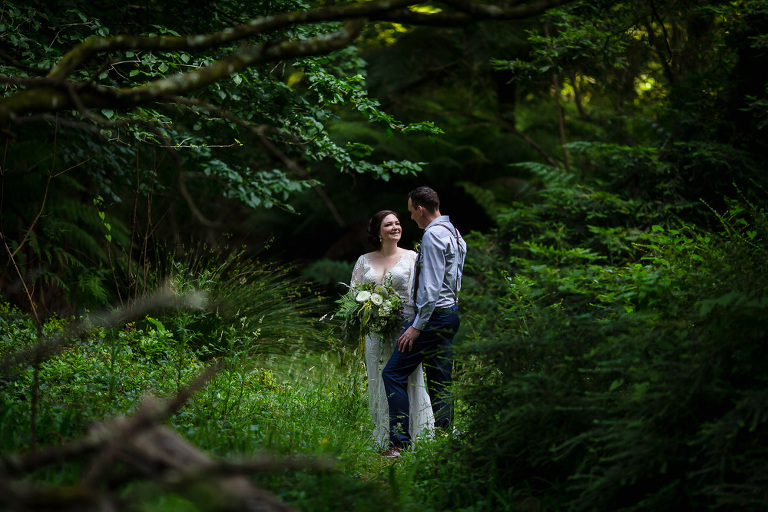 bride and groom talking to each other in small grass clearing in forest